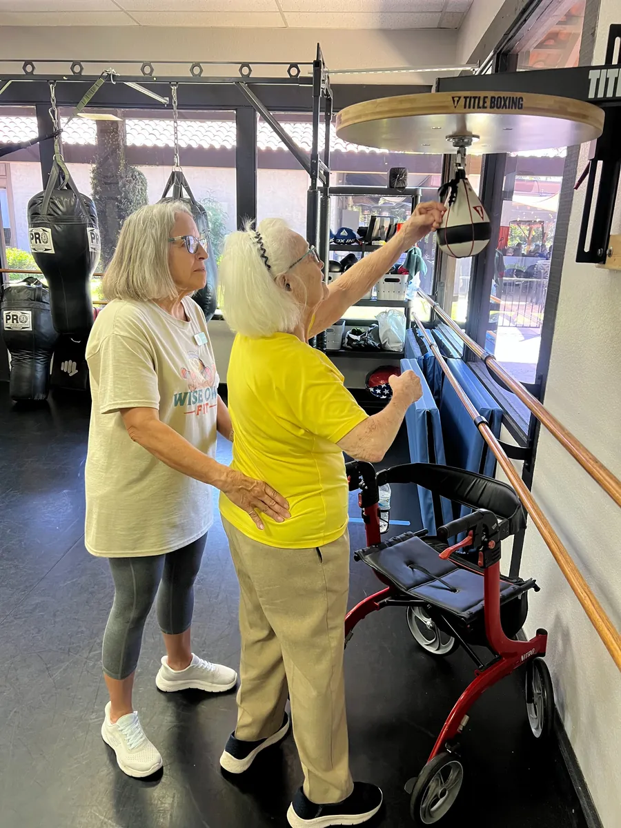 A coach helping a member on the speed bag